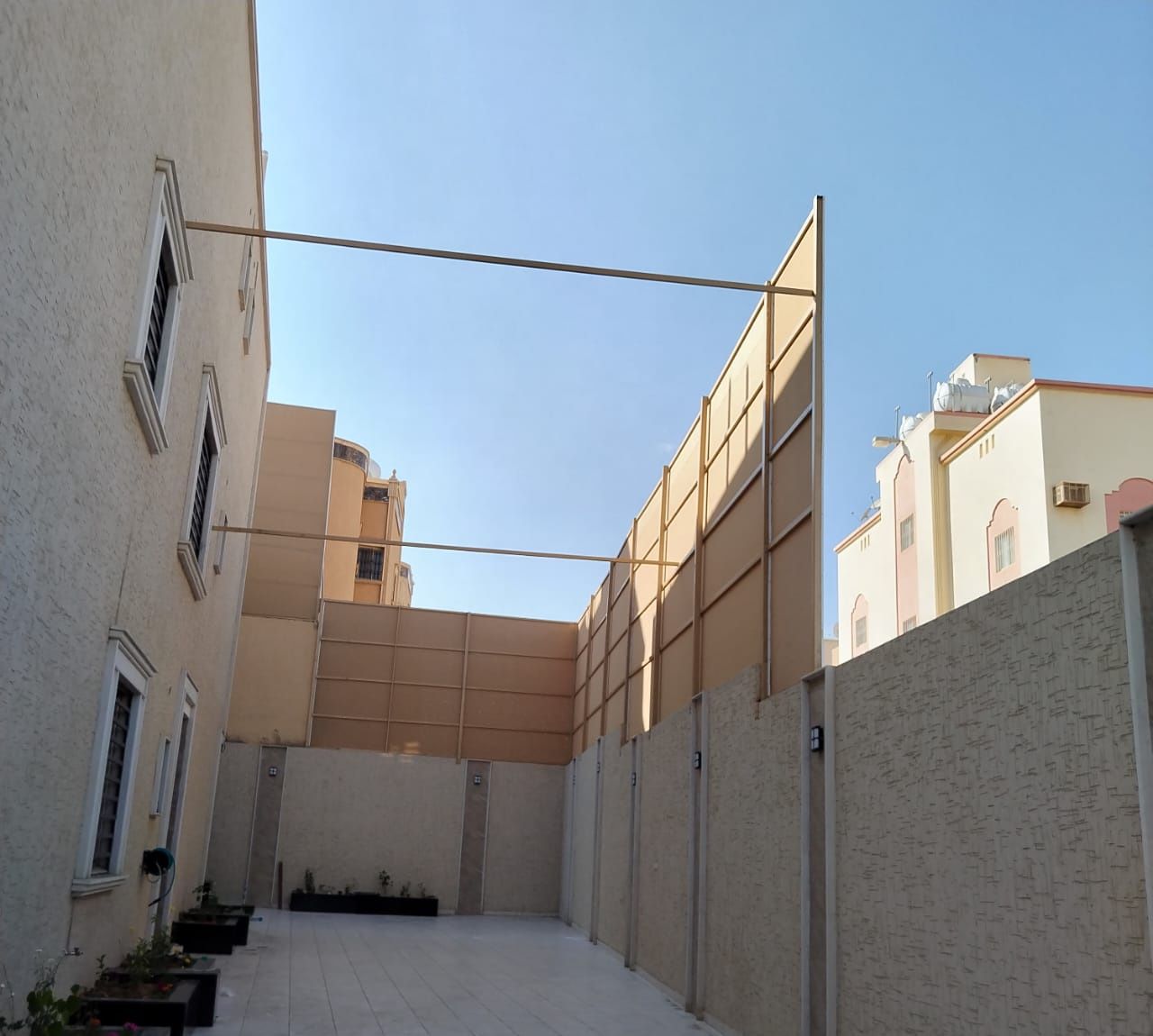 ساتر قماش بيج مرتفع بإطار حديد فوق سور حوش منزل لحجب الجيران